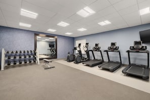 Ein Fitnessstudio mit Laufbändern, Crosstrainern und Kurzhanteln.
