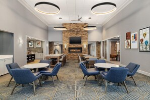 A modern indoor dining area with a stone wall, a fireplace, and a flat-screen TV mounted above it.