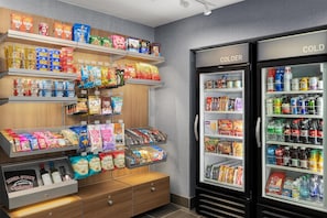 Una exhibición de snacks con diversos alimentos envasados y una sección refrigerada con bebidas.