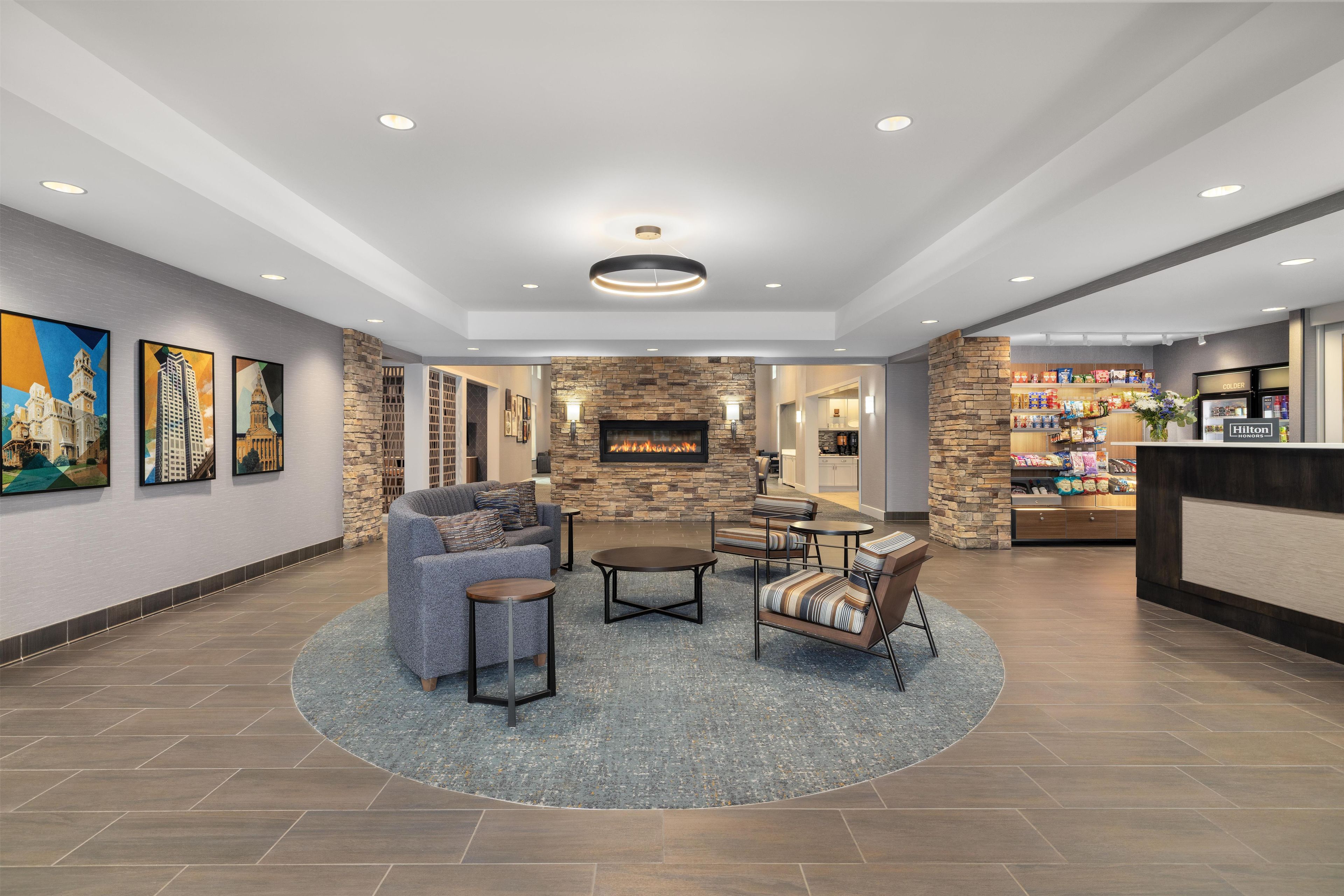 A hotel lobby with a stone fireplace, seating area, and artwork on the walls.