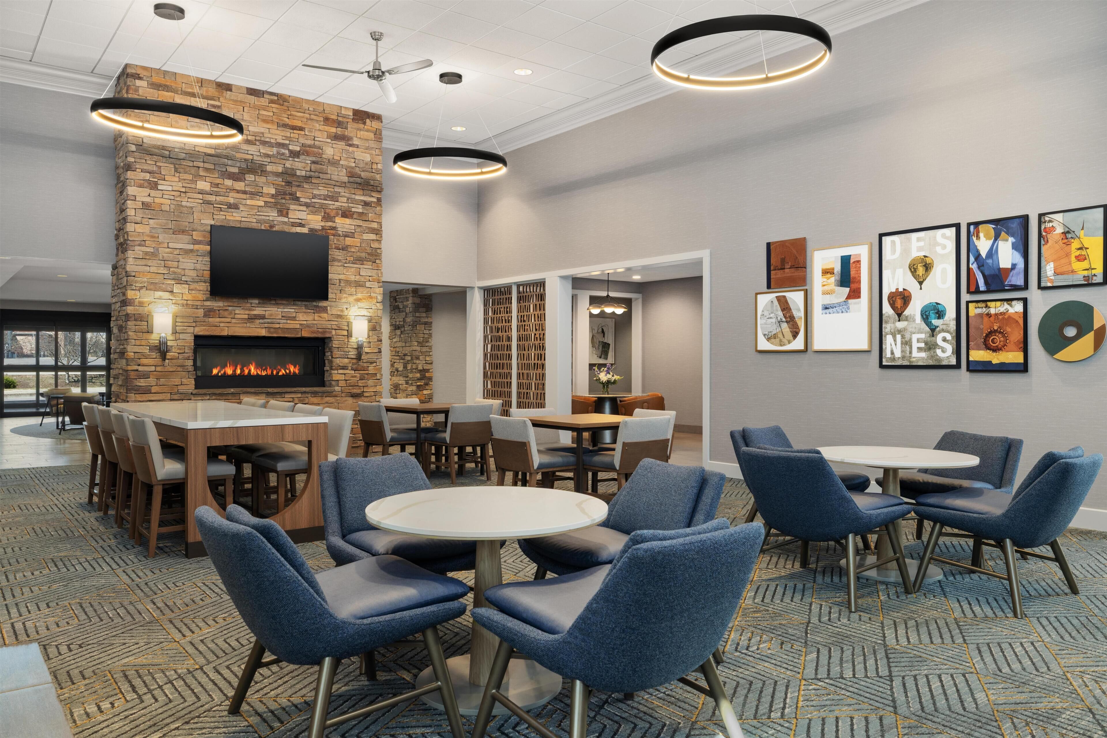 A hotel lobby with a stone fireplace, multiple seating areas, and artwork on the walls.
