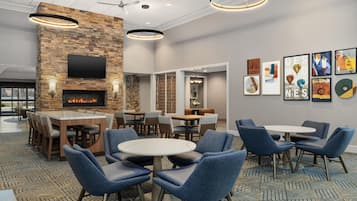 A hotel lobby with a stone fireplace, multiple seating areas, and artwork on the walls.