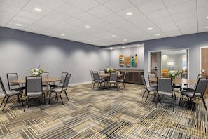 Un salón de conferencias de hotel con una mesa central y cuatro mesas circundantes, además de sillas.
