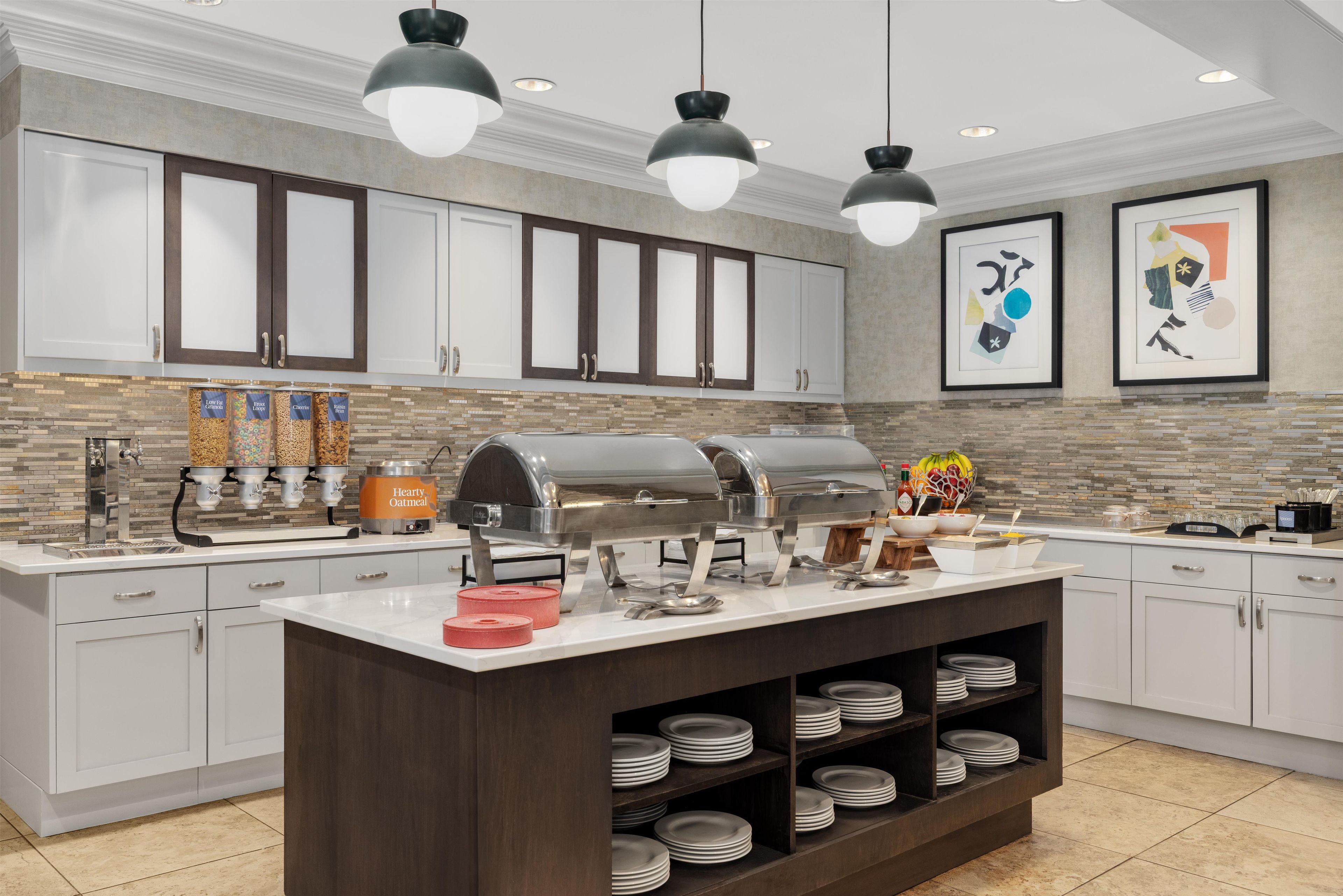 A modern kitchen with a central island, built-in cabinets, a coffee station, and a buffet setup.
