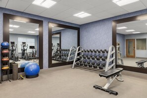 Un gimnasio con equipo de ejercicio, espejos y una pared con diseño geométrico.