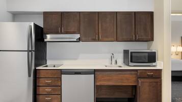 Cocina compacta con refrigerador, microondas, pileta y gabinetes de madera.