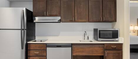 Cocina compacta con refrigerador, microondas, pileta y gabinetes de madera.
