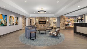 Un hall de hotel con chimenea de piedra, zona de estar, obras de arte en las paredes y un minibar.