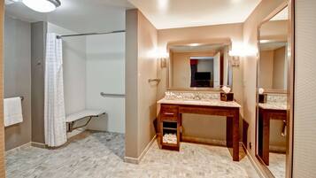 A bathroom with a shower, vanity with a mirror, and a towel rack.