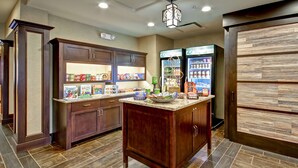 A kitchen with wooden cabinets, a granite countertop, and a refrigerator stocked with beverages. - Homewood Suites by Hilton Bridgewater/Branchburg (Branchburg)
