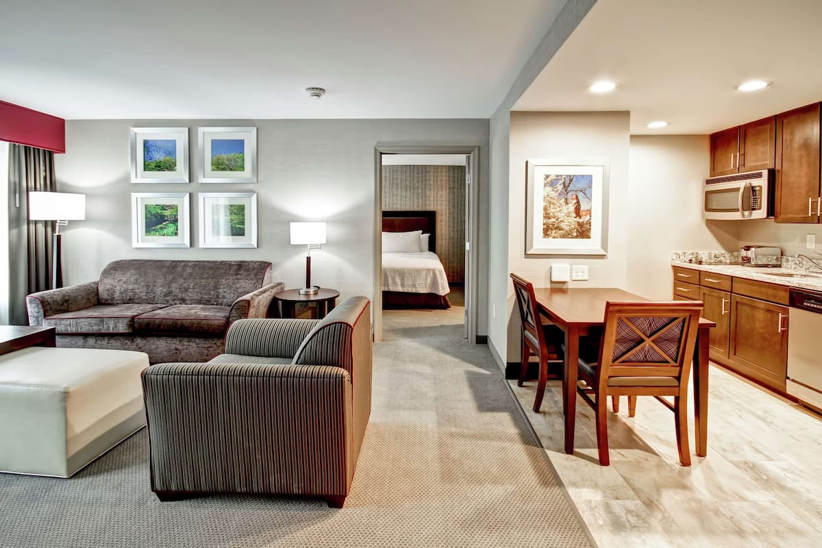 A hotel room with a living area, kitchenette, and a separate bedroom.