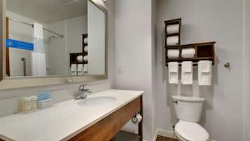 A bathroom with a white sink, mirror, and toilet. There are towels and toiletries on the counter.