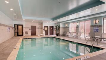 An indoor swimming pool with clear water, a tiled floor, and a ceiling with recessed lighting.