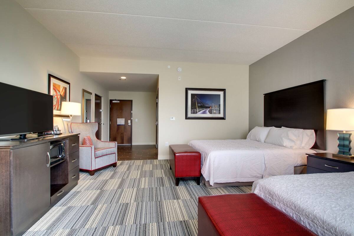 Habitación de hotel con dos camas, televisión, escritorio y una silla.