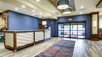 A reception area with a counter, a patterned rug, and a large glass door leading outside.