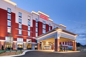 Un hotel Hampton Inn & Suites con una fachada moderna, ventanas amplias y un acceso cubierto.