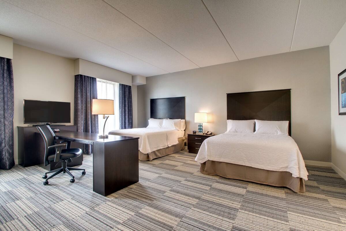 Una habitación de hotel con dos camas, un escritorio, un televisor y una lámpara.