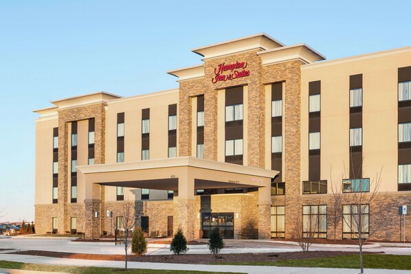 A Hampton Inn & Suites building with a brick facade, large windows, and a covered entrance.
