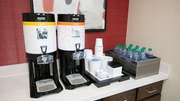 A coffee station with two coffee makers, disposable cups, and a water dispenser.