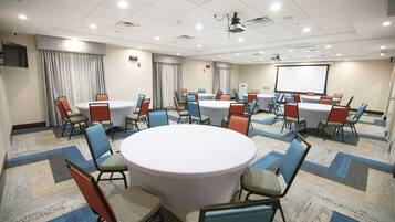 A conference room with round tables and chairs, a projector, and a screen.