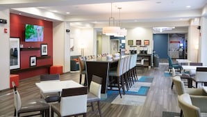 Un comedor moderno de hotel con una larga mesa común, mesas individuales y una zona de bar.
