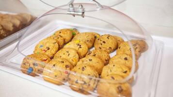 Un recipiente de plástico transparente con tapa de cristal que contiene una variedad de galletas con trozos visibles de chocolate y confeti de colores.