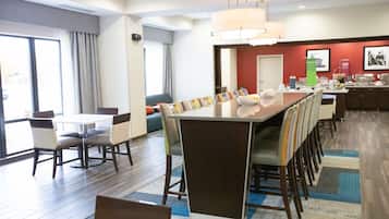 Comedor de hotel con una larga mesa, sillas y una barra de buffet.