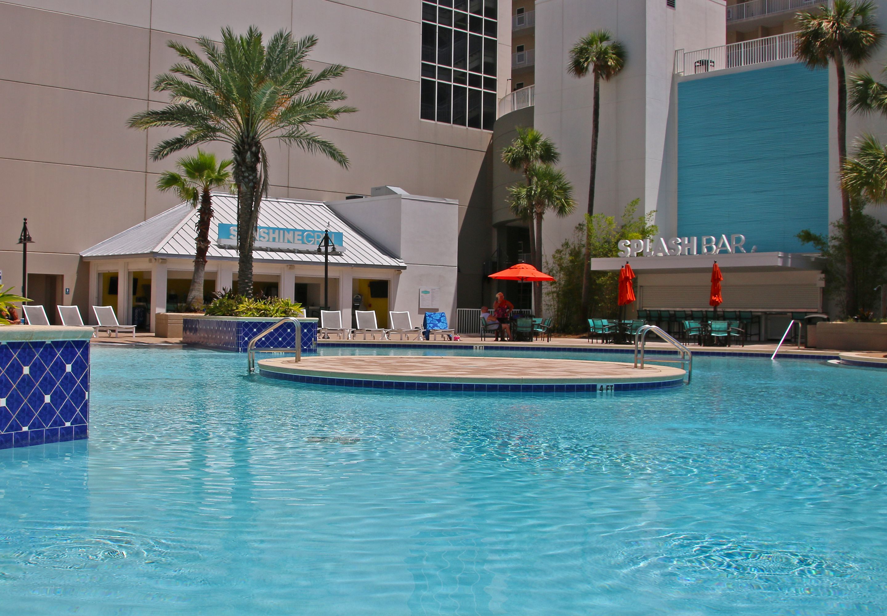 A swimming pool with lounge chairs and a building with a sign that reads "SHINE".