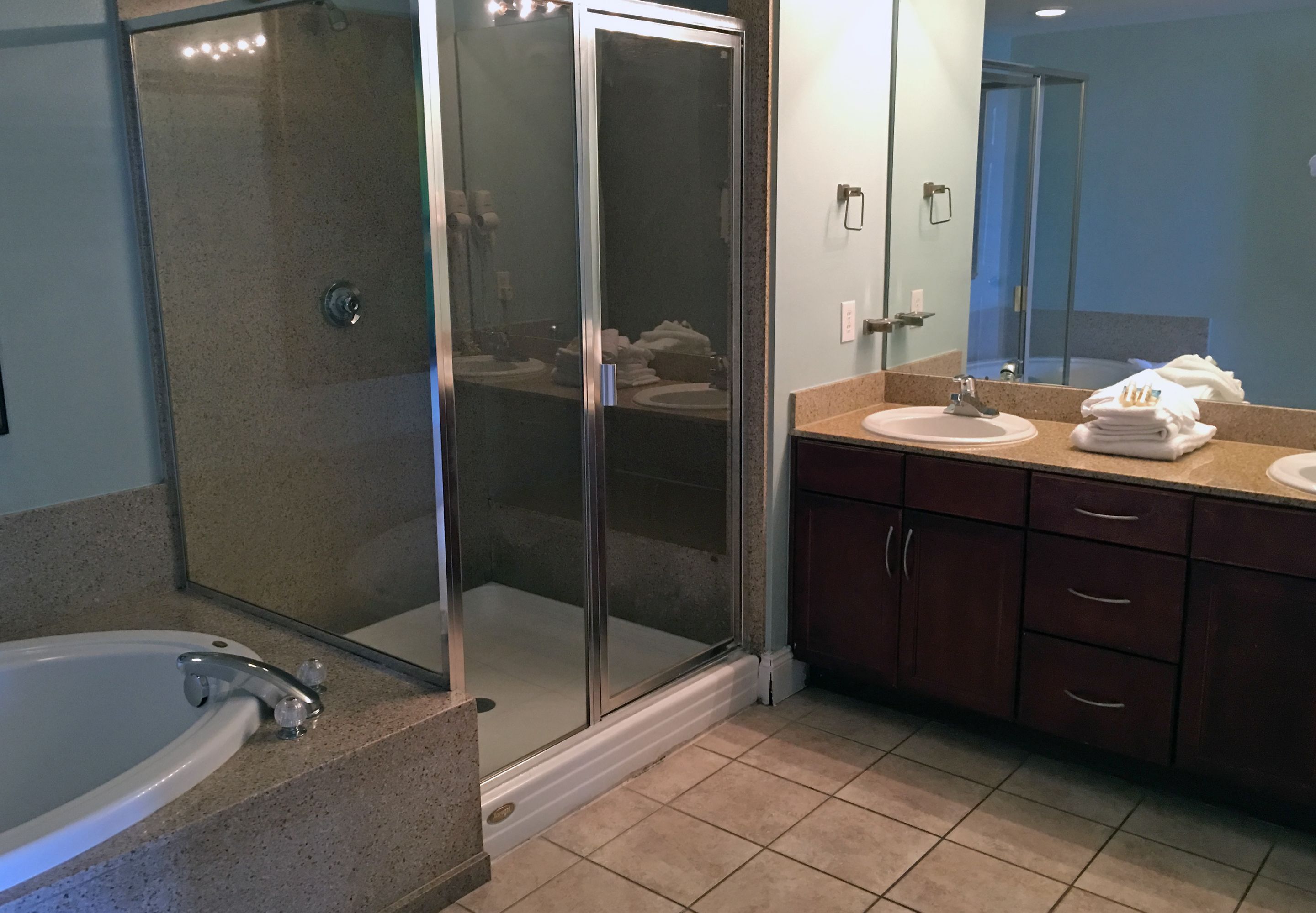 Un baño moderno con ducha envuelta en vidrio, bañera y tocador con lavabo y espejo.