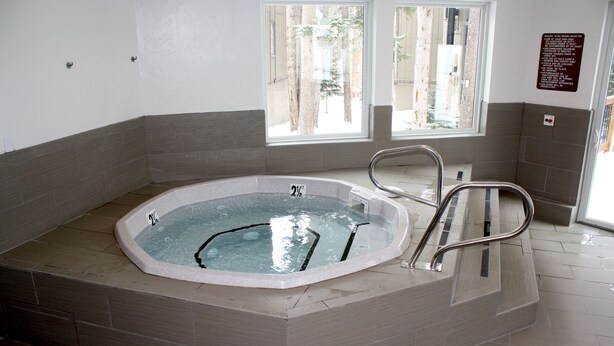 Ein Whirlpool mit Metallleiter, ein Fenster mit Blick auf Bäume und ein Schild an der Wand.