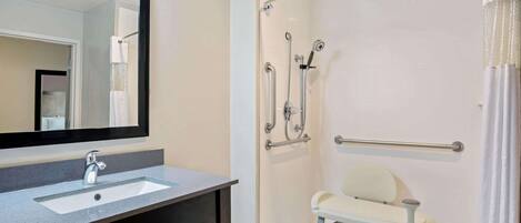 A bathroom with a sink, mirror, shower, and toilet.