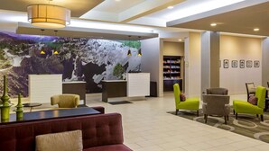 Vestíbulo de hotel con recepción, zona de estar y un gran mural en la pared.