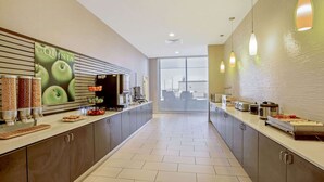 Una cocina moderna con una encimera amplia, diversos alimentos y un ventanal grande.