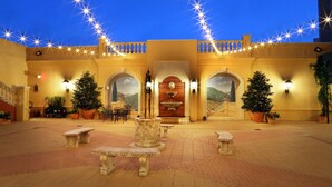 A courtyard with stone benches, potted plants, and a fountain. - Hotel Viata (Austin)