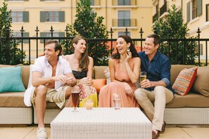 Un gruppo di persone sedute su un divano in vimini con un tavolo davanti, che sorseggiano delle bevande.