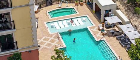 Une piscine sur le toit, dotée de plusieurs couloirs de nage, de chaises longues et d’un petit bâtiment à l’extérieur blanc.