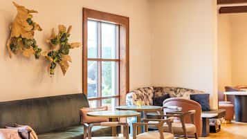 Una habitación acogedora con suelo de madera, un sofá verde, una mesa de comedor con sillas y un ventanal grande.