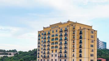 Un hotel de varios pisos con fachada amarilla, múltiples balcones y un césped bien cuidado al frente.