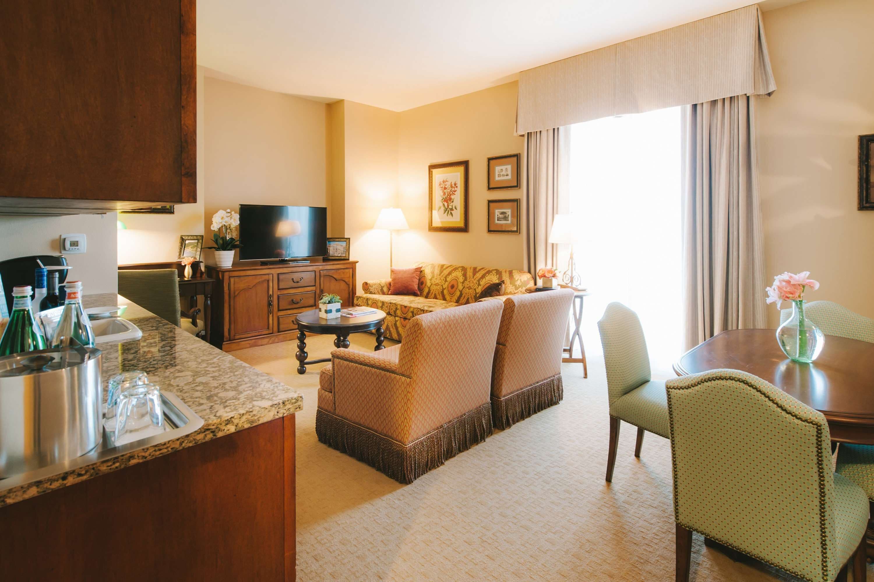 Una habitación de hotel con cocina, sofá, mesa de comedor y televisor.
