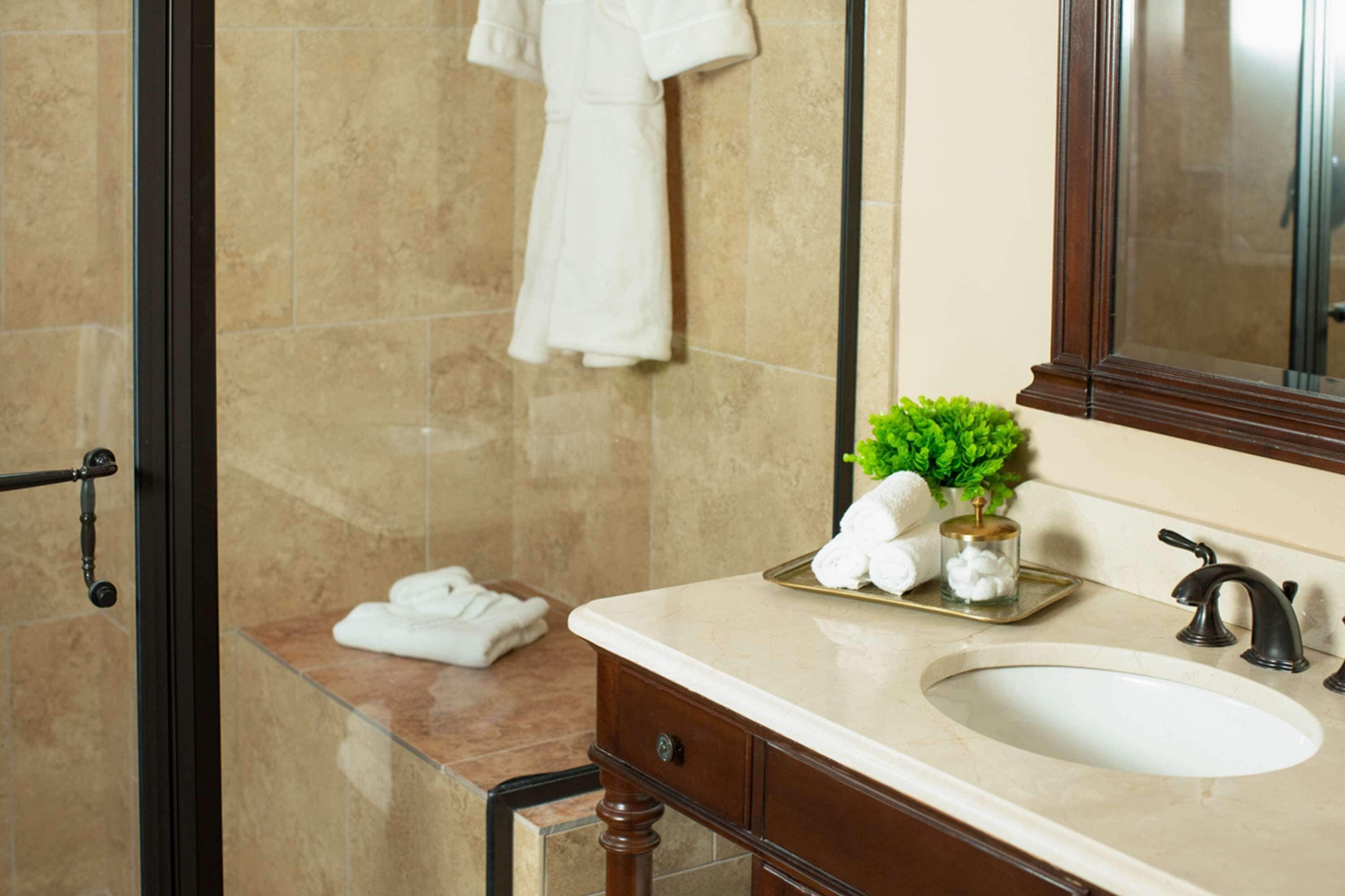 A bathroom with a beige sink, a mirror, and a towel rack.