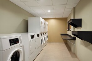 A laundry room with multiple washing machines and dryers, a tiled floor, and a wall-mounted shelf. - Staybridge Suites Midland by IHG (Midland)