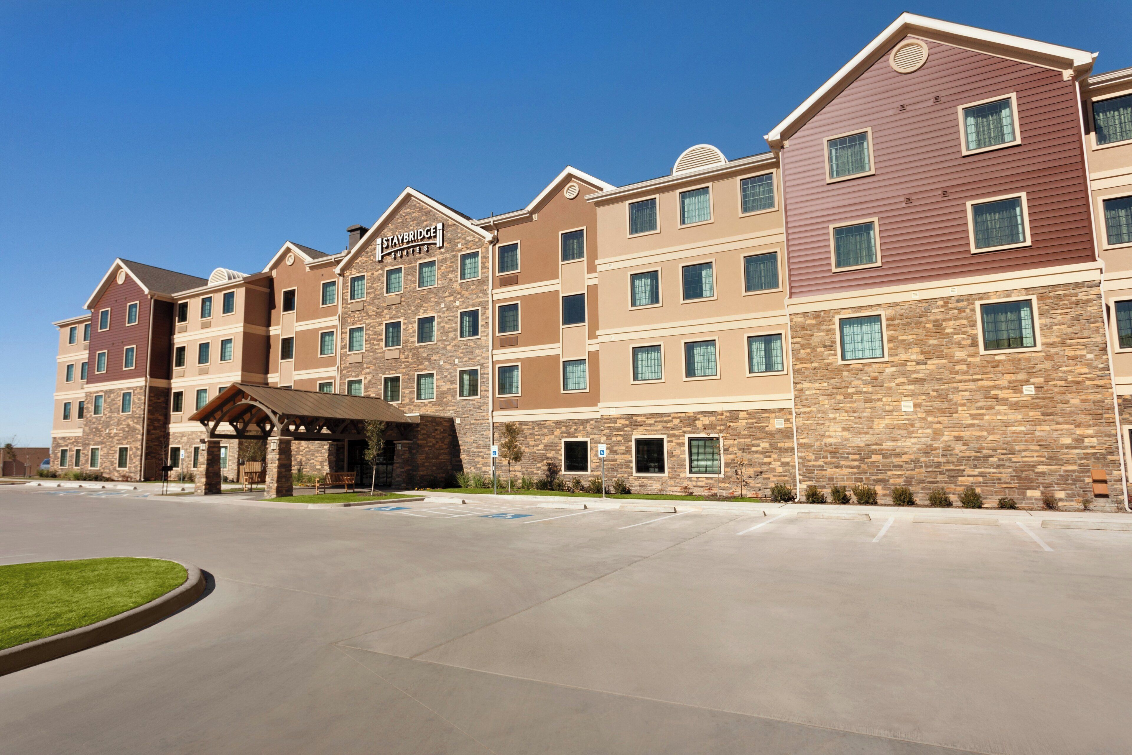 A Staybridge Suites hotel with a stone facade, multiple windows, and a covered entrance area.
