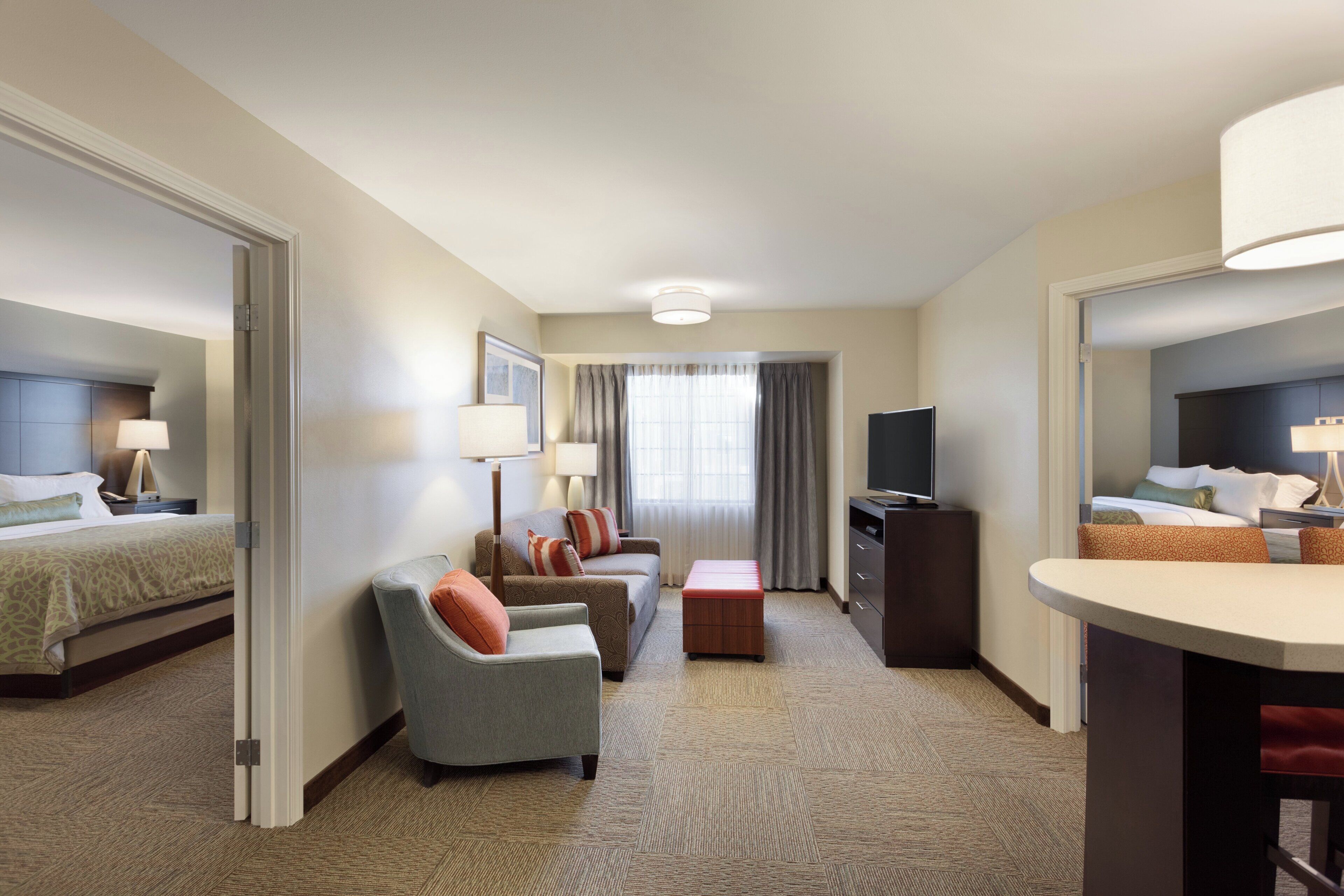 A hotel room with a bed, a sofa, a TV, a desk, and a chair.
