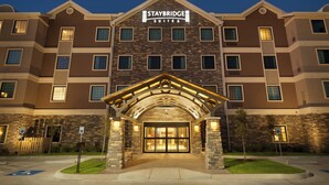 A Staybridge Suites hotel with a brick facade, multiple windows, and a well-lit entrance.