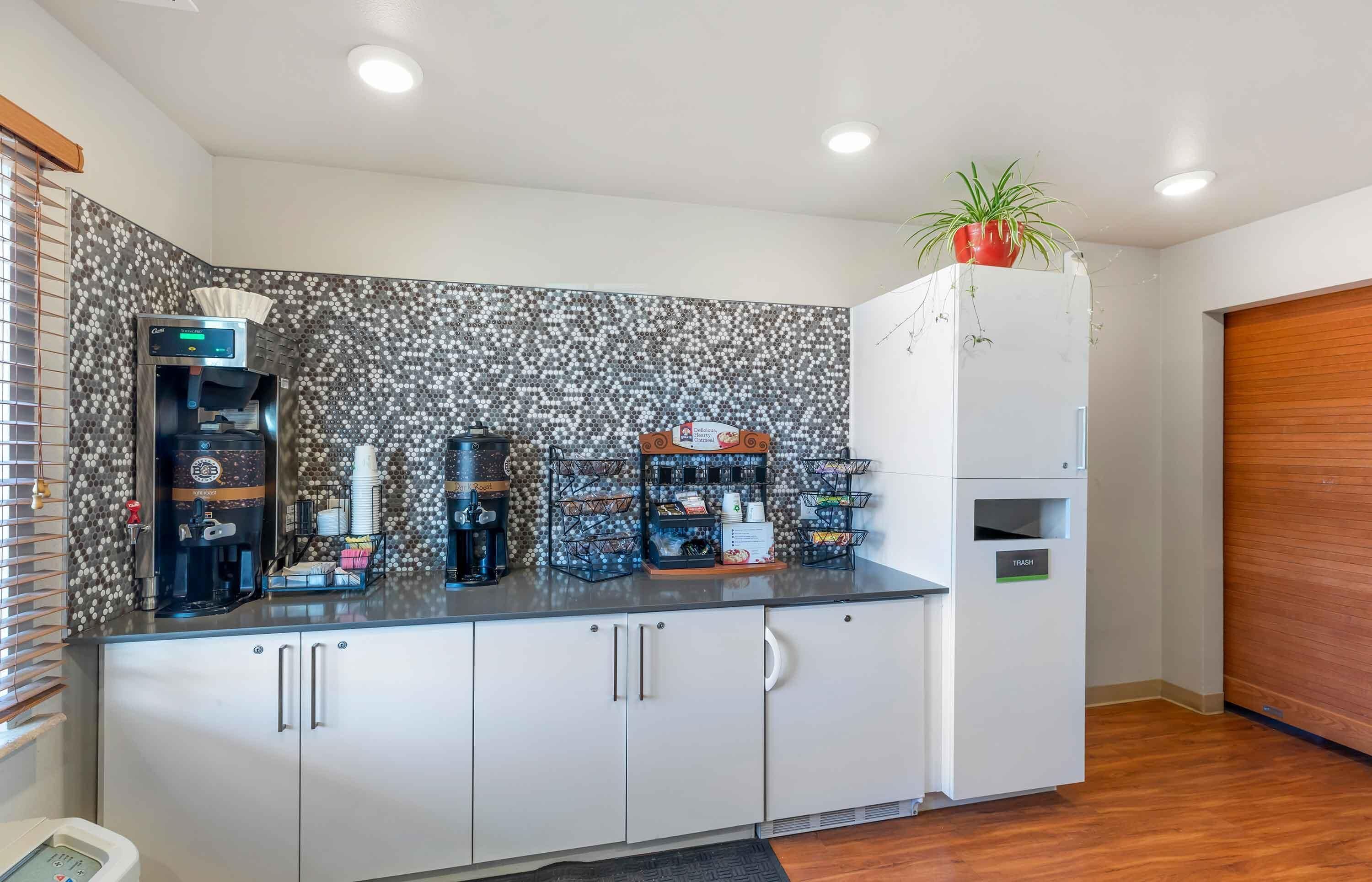 A kitchenette with a coffee machine, a toaster, and a refrigerator.