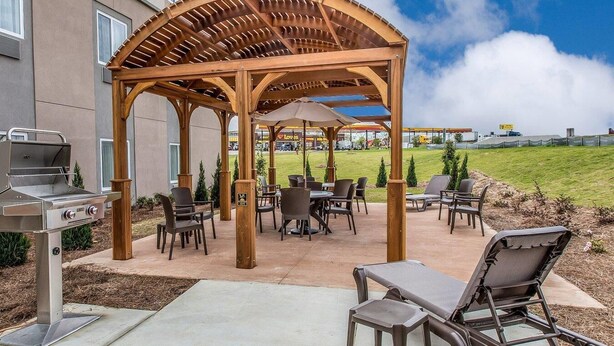 Une terrasse extérieure dotée d’une pergola en bois, de sièges et d’un barbecue.