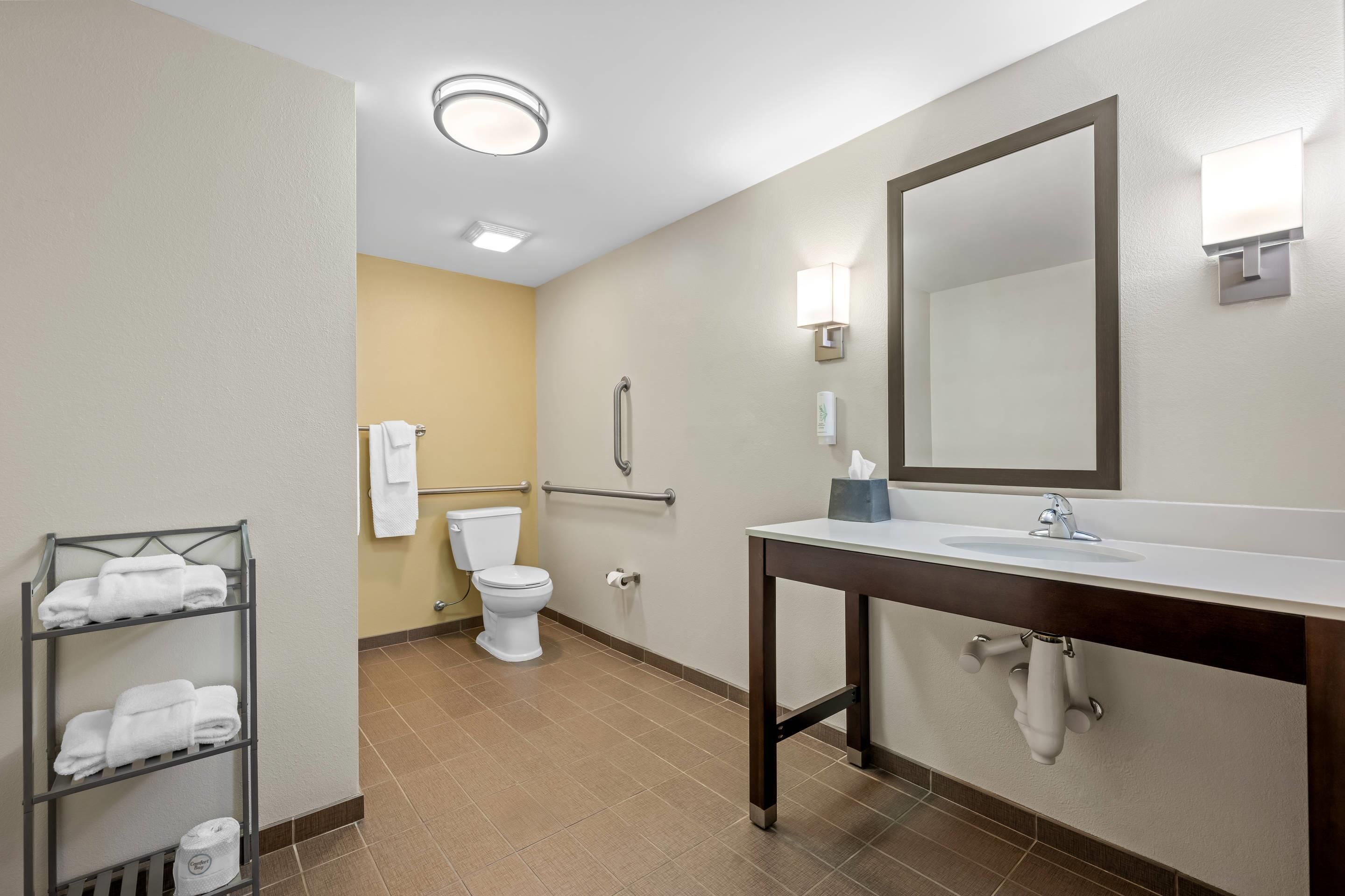 A bathroom with a white sink, a mirror, a towel rack, and a toilet.