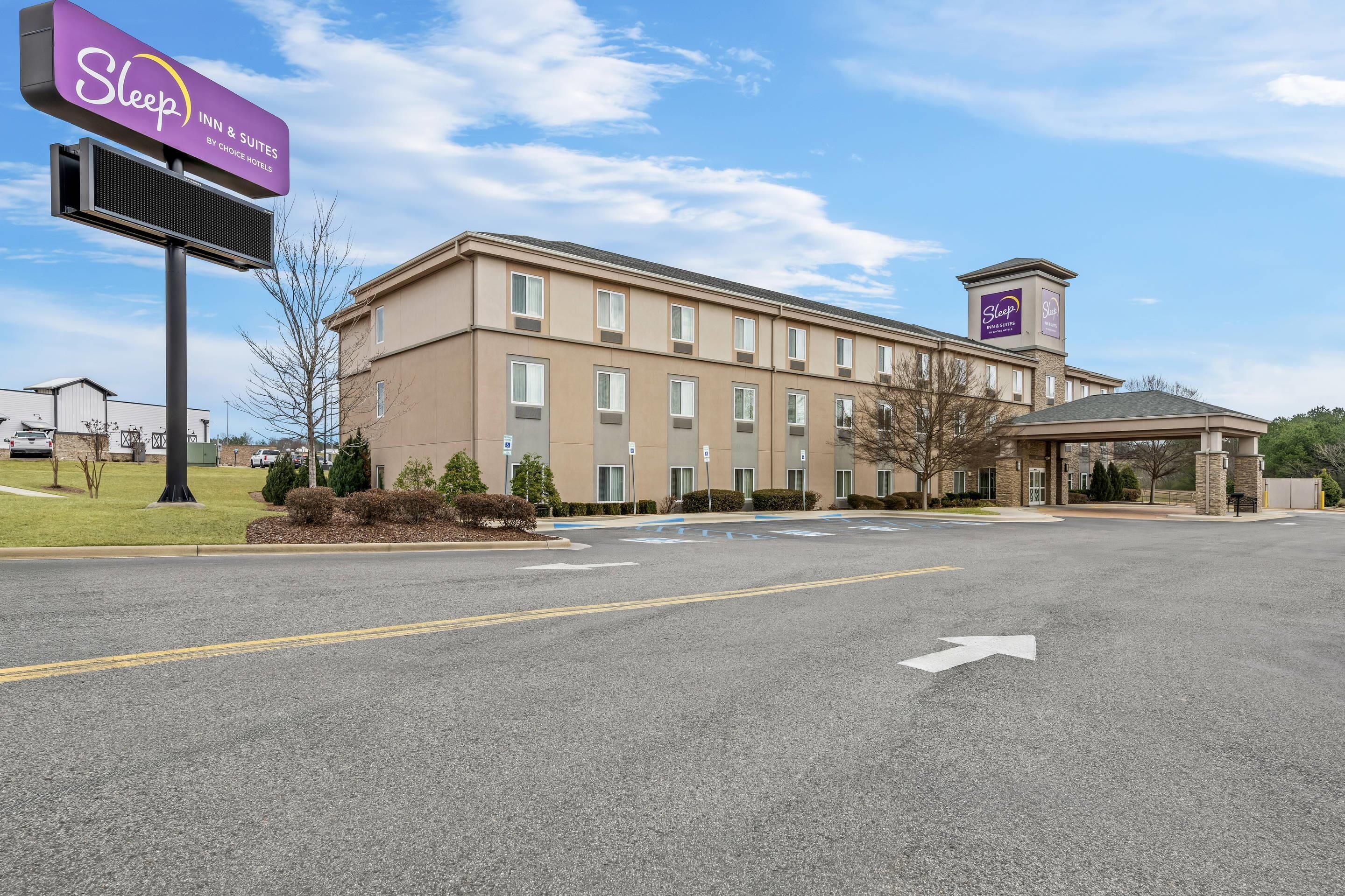 A Sleep Inn & Suites hotel with a modern design, featuring a large signboard, a covered entrance, and a parking lot.