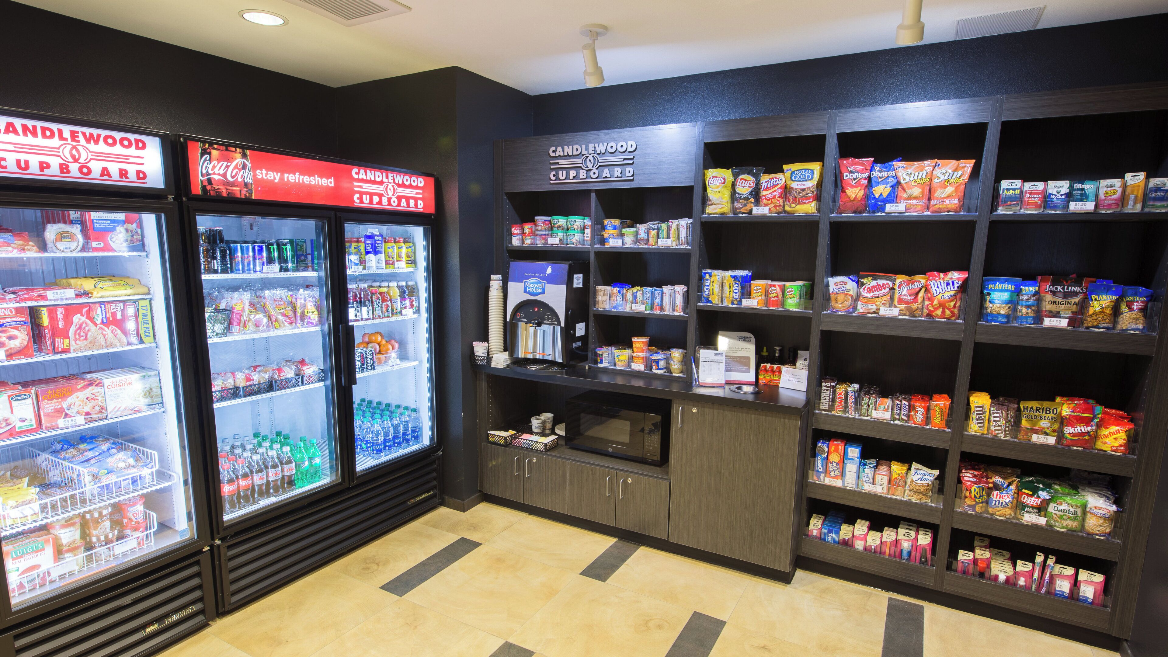 A convenience store with refrigerated beverage coolers, snack shelves, and a coffee machine.