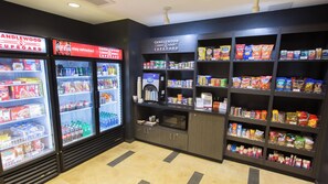 Ein Kiosk mit Kühlregalen für Getränke, Verkaufsregalen für Snacks und einer Kaffeemaschine.